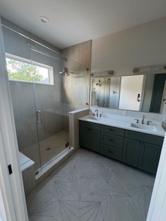 Primary bathroom with glass-enclosed shower and green vanity Primary bathroom with glass-enclosed shower and green vanity